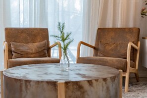 Two brown armchairs with wooden frames and cushions, positioned around a round wooden table with a glass vase in the center. - Disney Getaway 4BD Home wITH Private Pool and BBQ (Kissimmee)