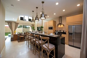A modern kitchen with a central island, stainless steel appliances, and pendant lighting. - The Luxury Escape 3BD All-Suite Home with BBQ (Kissimmee)