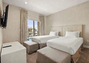 Een hotelkamer met drie bedden, een televisie en uitzicht op buiten.