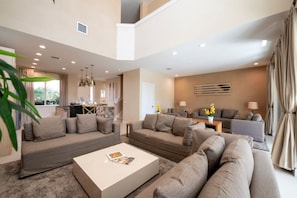 A spacious living room with a sofa set, a coffee table, and a dining area in the background. - The Luxury Escape 3BD All-Suite Home with BBQ (Kissimmee)