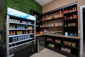 Eine Selbstbedienungs-Getränkestation mit einer Auswahl an Getränken und Snacks, darunter Flaschenwasser, Säfte und Energydrinks.