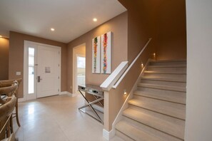 Un interior moderno con una escalera, una puerta y una parrilla fijada a la pared.