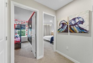 A hallway with a bed, a door, and two paintings on the wall. - 4BD with Pool and BBQ Mickey and Stitch Magic Top Location (Kissimmee)