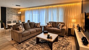 Ein modernes Wohnzimmer mit zwei Sofas, einem Couchtisch und einem Essbereich mit Tisch und Stühlen.