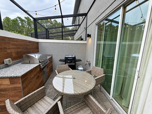 Eine Außenpatio mit Grill, Sitzgelegenheit und Glastür.