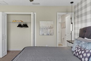 Un dormitorio con cama, armario, un cuadro y pared estampada.