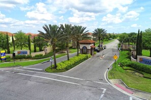 Une route menant à une entrée fermée par un portail, bordée de palmiers et sur laquelle on peut lire une enseigne indiquant « Suterra Resort ».