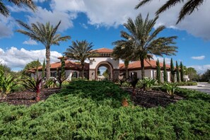 A Mediterranean-style building with an arched entrance, surrounded by lush greenery and palm trees. - 5BD Family Home with Pool BBQ and Themed Rooms (Davenport)