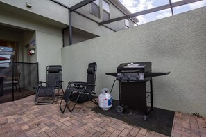 An outdoor patio with a grill, folding chairs, and a water dispenser. - 5BD Family Home with Pool BBQ and Themed Rooms (Davenport)