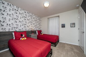 A room with two beds, a nightstand, a Mickey Mouse plush toy, and a wall with Mickey Mouse sketches. - 5BD Family Home with Pool BBQ and Themed Rooms (Davenport)
