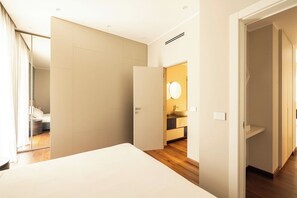 A modern hotel room with a large bed, a walk-in closet, a bathroom with a mirror, and a wooden floor. - Icona Lagrange | Egyptian Museum & Piazza SanCarlo (Turin)
