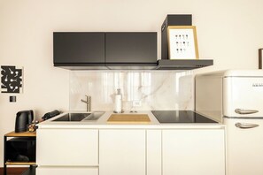 A kitchen with a black range hood, a white refrigerator, and a wooden cutting board on the countertop. - Icona Lagrange | Egyptian Museum & Piazza SanCarlo (Turin)