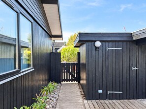 A wooden deck leading to a dark wooden shed with a white light fixture and a metal latch. - 6 Person Holiday Home in Juelsminde (Juelsminde)