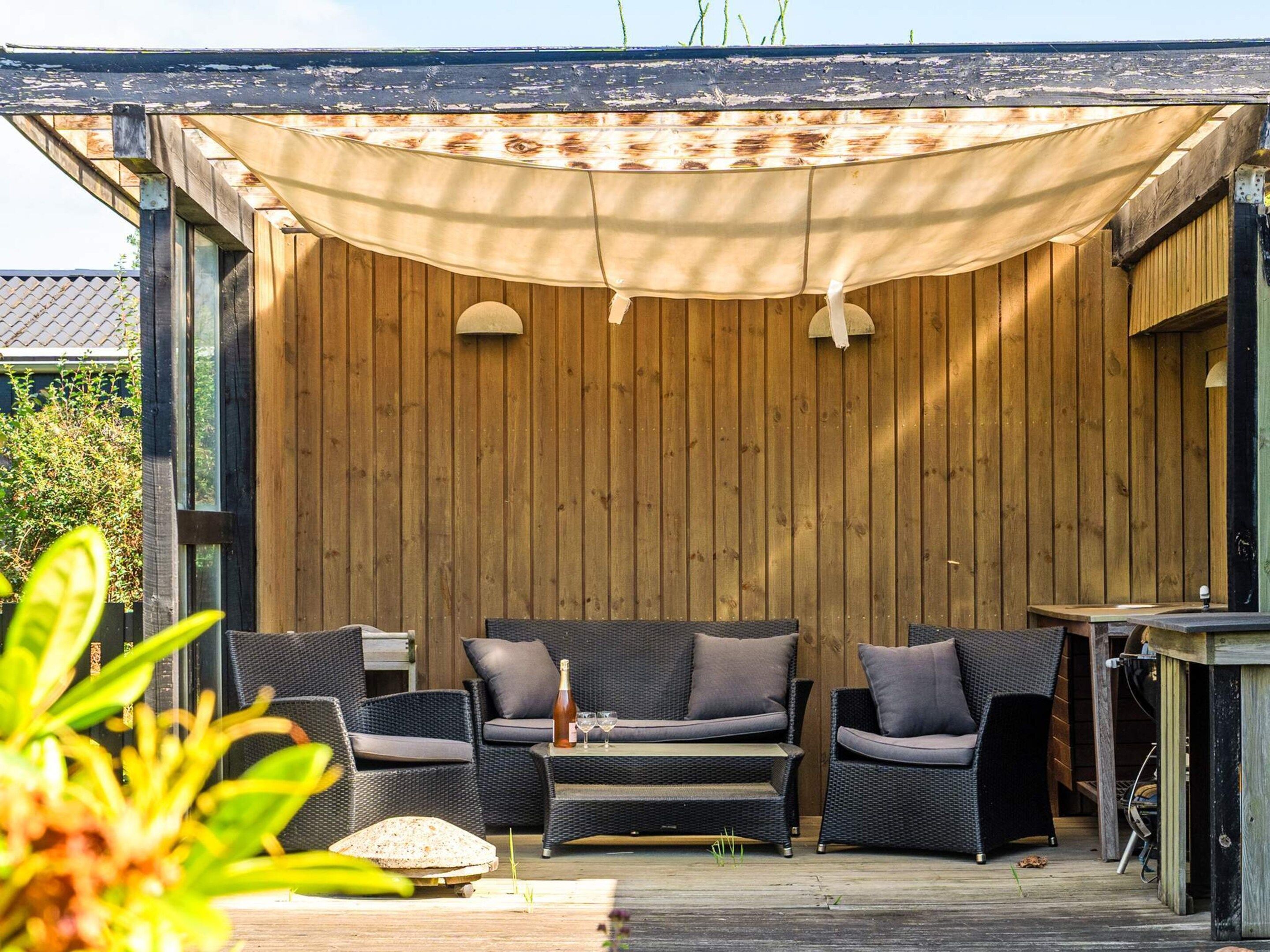 An outdoor seating area with wicker furniture and a wooden backdrop.