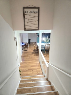 Eine Treppe führt zu einem Essbereich, über dem ein Schild mit der Aufschrift 'live a good story' steht.
