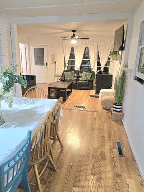 A living room with a sofa, a dining table with chairs, a ceiling fan, and a window with curtains. - Wabana Sage House Grand Rapids, MN by the forest (Grand Rapids)