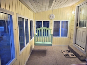 A porch with a green bench, a clock, and a door with a glass panel. - Wabana Sage House Grand Rapids, MN by the forest (Grand Rapids)