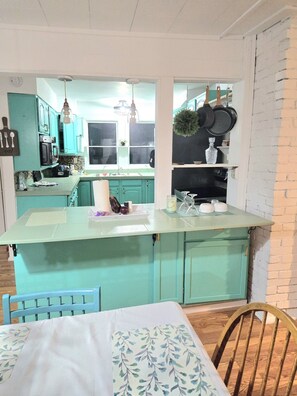 A kitchen with teal cabinets, a central island, and hanging lights. - Wabana Sage House Grand Rapids, MN by the forest (Grand Rapids)