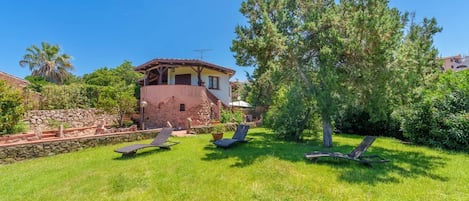 Ein Haus mit Mauerwerk, einer Holzterrasse und einem Baum im Garten.