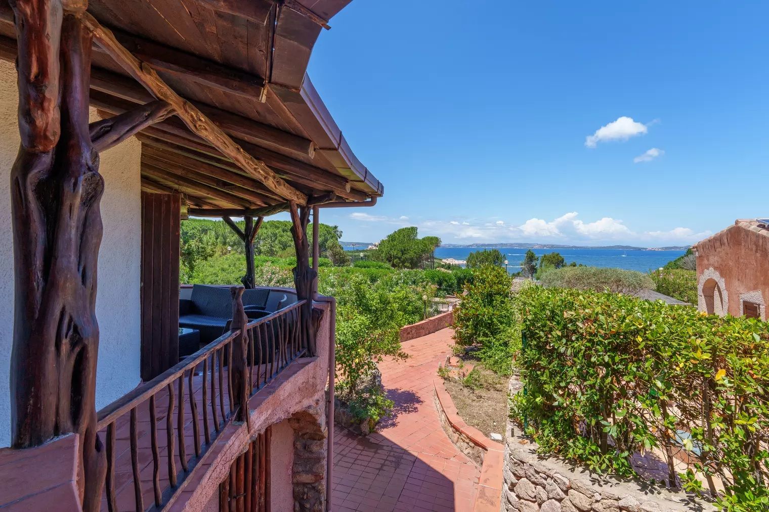 A wooden balcony with a view of a coastal landscape.