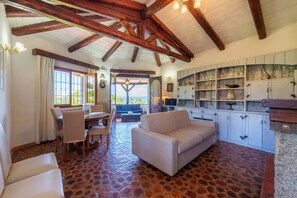 Una habitación amplia con comedor, sofá y cocina con estantes abiertos.