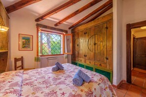 A bedroom with a bed, a window with a view, a wooden wardrobe, and a radiator. - Villa Baja (Baja Sardinia)