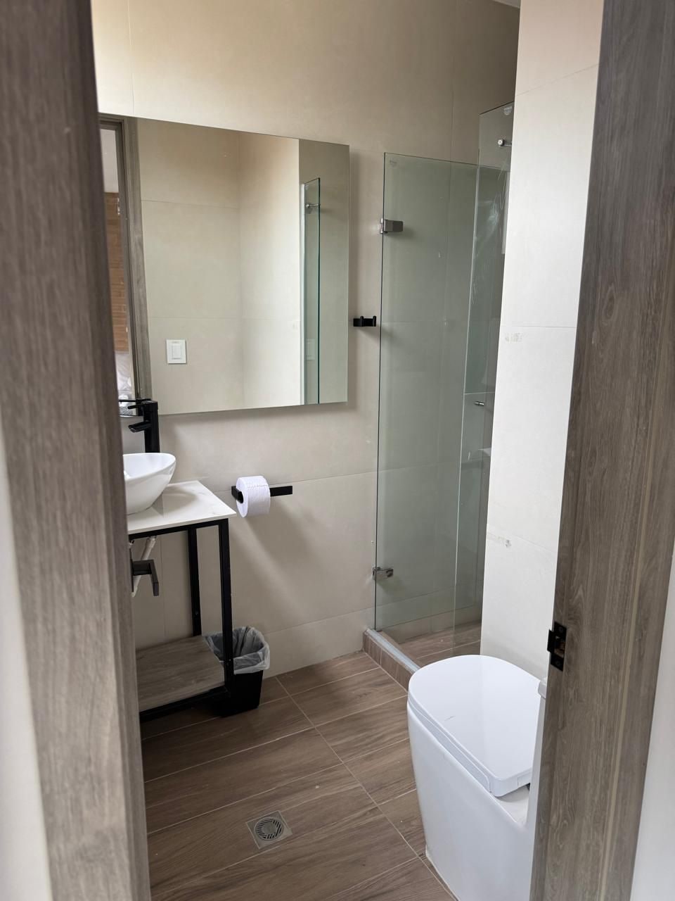 A bathroom with a toilet, sink, and glass shower enclosure.