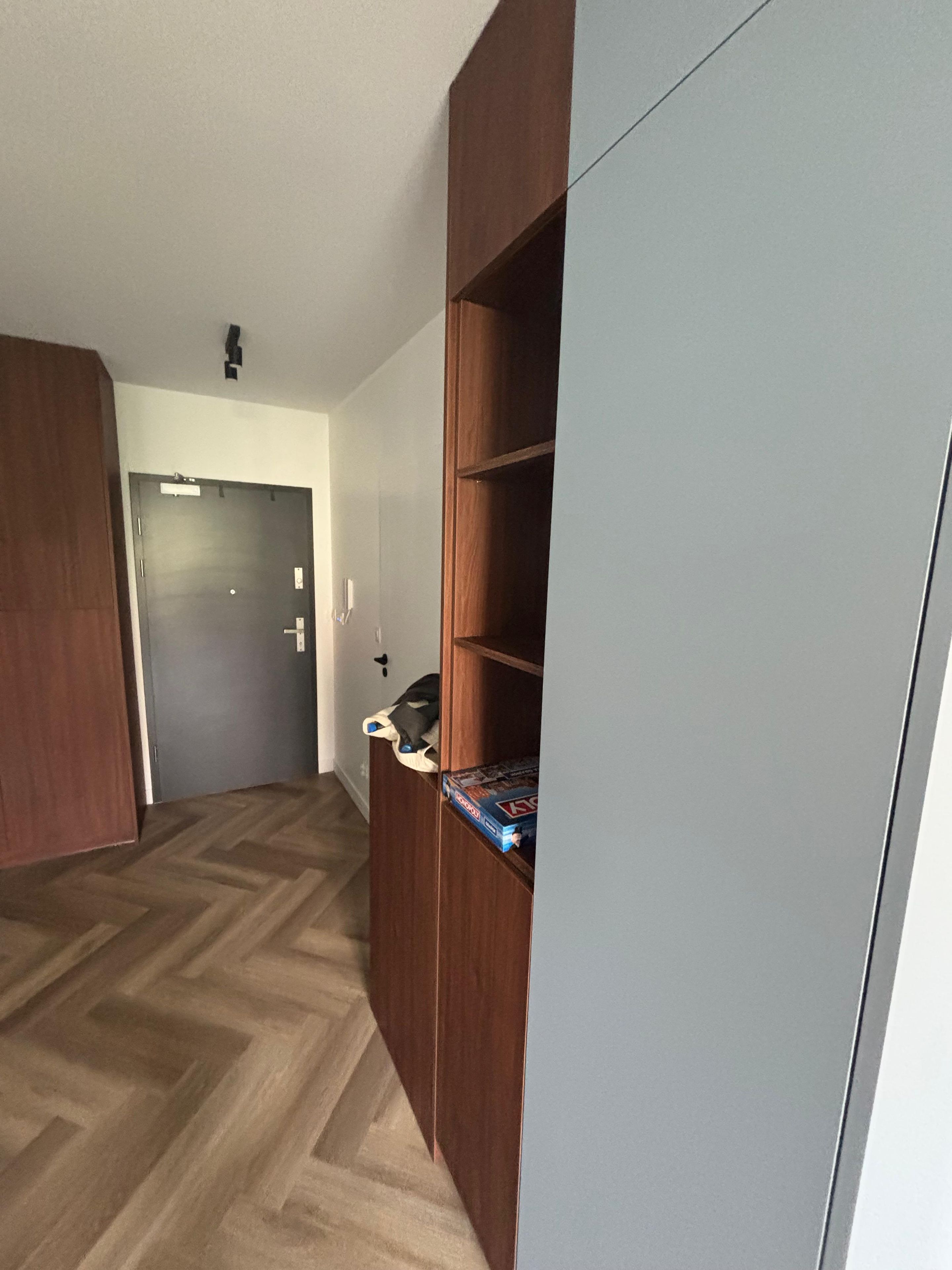 Una habitación con un armario de madera, una puerta y un estante con un juego de mesa.