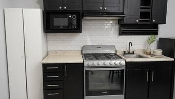 Une cuisine avec des meubles de couleur noire, un réfrigérateur blanc, une cuisinière et un four à micro-ondes.