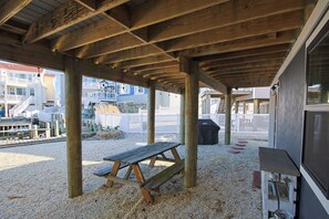 A covered outdoor area with wooden beams, a picnic table, and a grill. - Cozy 2-bedroom house on beautiful lagoon (Stafford Township)