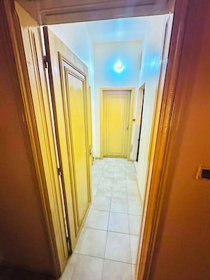 A narrow hallway with a tiled floor leading to a door at the end.