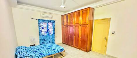 A room with a bed, wardrobe, and a small table.