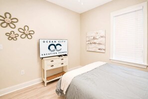 A bedroom with a bed, a dresser, a flat-screen TV, and wall art. - Laguna Vista 304 (Ocean City)
