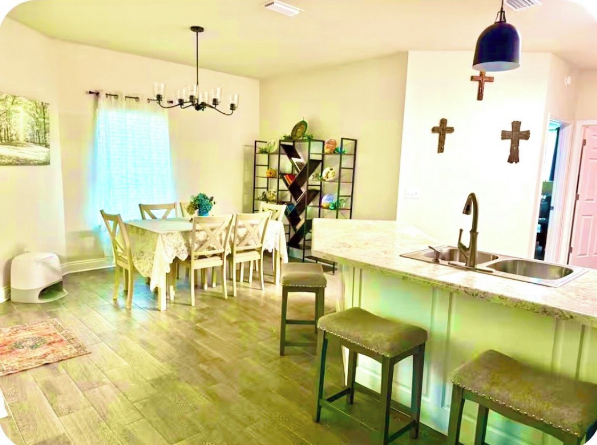 A kitchen with a bar area, a dining table with chairs, and a chandelier.