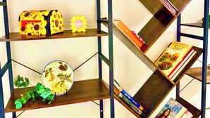 Een metalen boekenplank met meerdere planken, waarvan sommige boeken en decoratieve objecten bevatten.