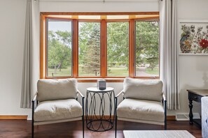 A room with two armchairs facing a large window with a view of trees and a lawn. - Family Home Near Dells Waterparks | Papas' Legacy (Wisconsin Dells)