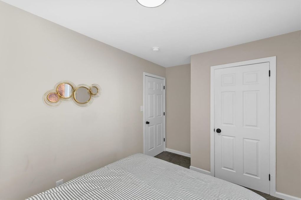 A bedroom with a bed, two doors, and wall-mounted light fixtures.