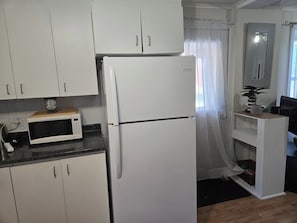 A kitchen with white cabinets, a white refrigerator, a microwave, and a small wooden countertop. - Quiet 2-bedroom near Ottawa – Wi-Fi and free parking (Gatineau)