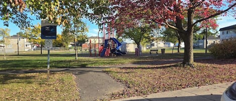 A park with playground equipment, a parking sign, and a pathway.