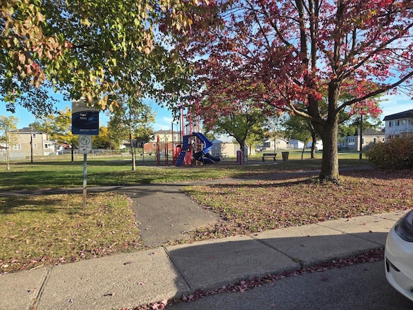 A park with playground equipment, a parking sign, and a pathway.