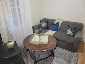 A living room with a grey sofa, a round coffee table, and a patterned rug.