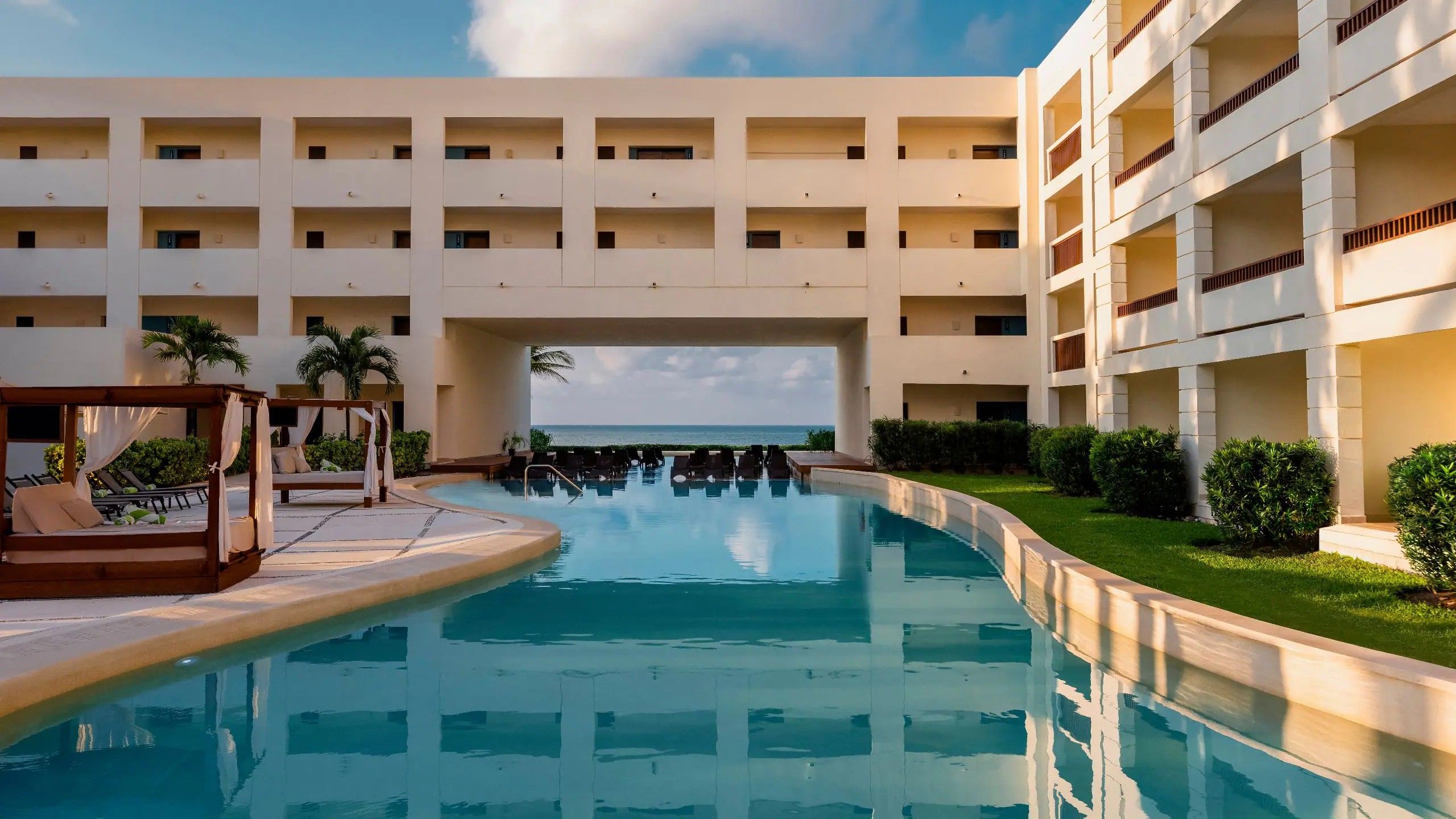 Un hotel con piscina, varios balcones y vista al mar.