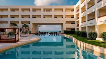 A hotel with a swimming pool, multiple balconies, and a view of the sea.