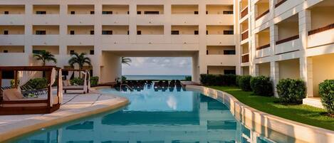 Un hotel con piscina, varios balcones y vista al mar.