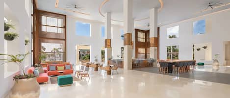 A spacious lobby with a central seating area, a bar, and large windows providing natural light.