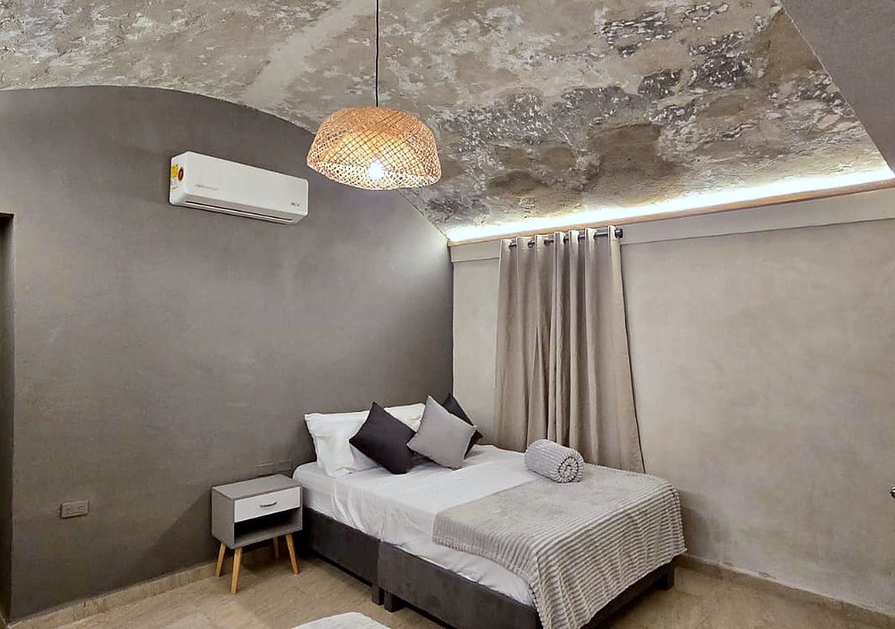 Een slaapkamer met een bed, nachtkastje en hanglamp.