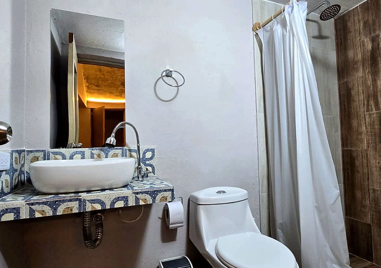 Une salle de bain avec un lavabo blanc, des toilettes et un rideau de douche.