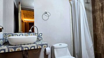 Une salle de bain avec un lavabo blanc, des toilettes et un rideau de douche.