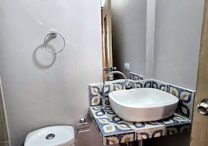 Et badeværelse med en hvid vask, toilet og spejl.