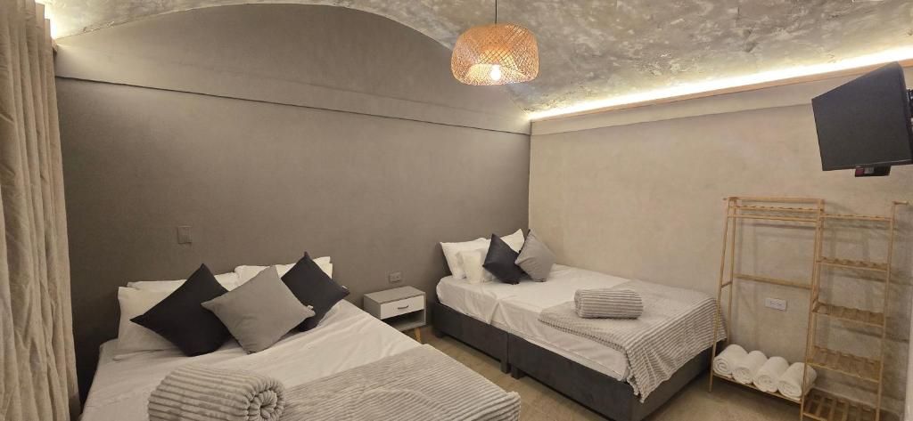 A hotel room with two beds, a TV, and a ceiling light fixture.